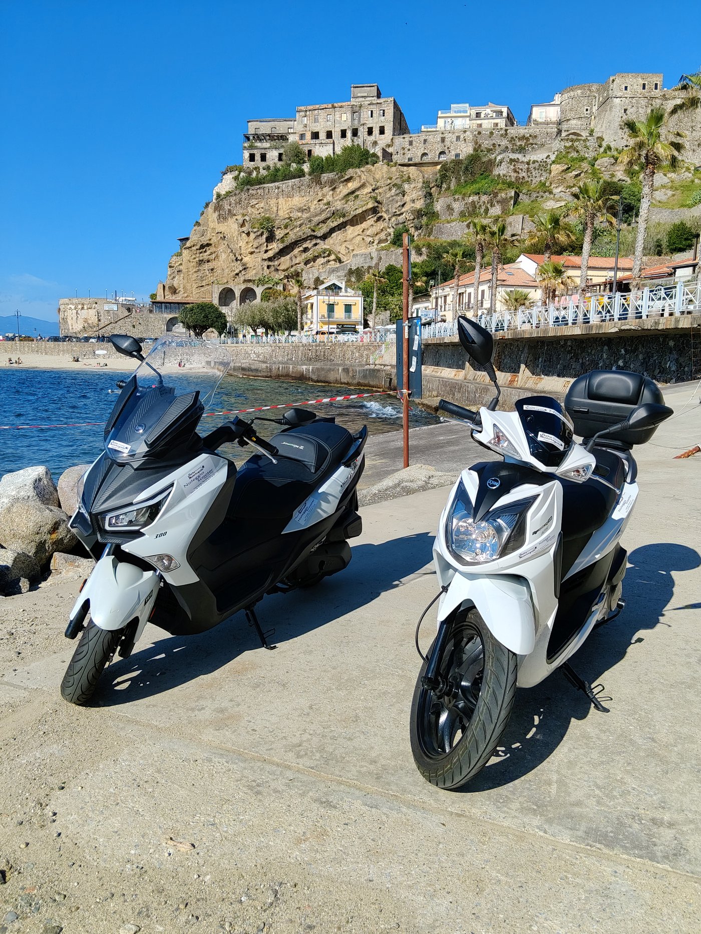 Due scooter pronti per il noleggio moto a Lamezia Terme, fermi davanti al mare